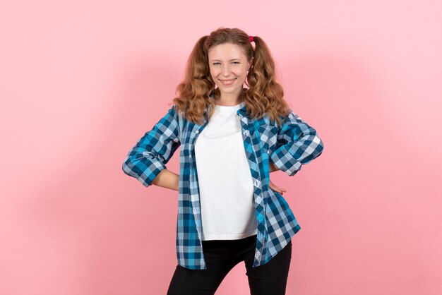 Vista frontal mujer joven en camisa a cuadros azul posando sobre fondo rosa emoción niña modelo moda juvenil niño