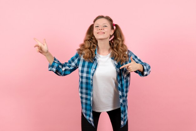 Vista frontal mujer joven en camisa a cuadros azul posando sobre el fondo rosa juventud emoción niña niño modelo moda