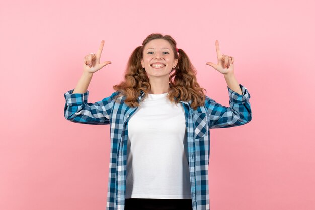 Vista frontal mujer joven en camisa a cuadros azul posando sobre fondo rosa mujer emoción modelo moda niña color