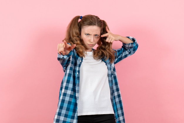 Vista frontal mujer joven en camisa a cuadros azul posando sobre fondo rosa mujer emociones modelo moda niñas color