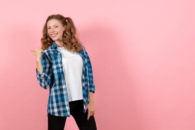 Vista frontal mujer joven en camisa a cuadros azul posando sobre el fondo rosa niño emoción modelo moda mujer color