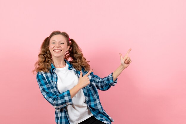 Vista frontal mujer joven en camisa a cuadros azul posando sonriendo sobre fondo rosa mujer emociones niñas color modelo moda