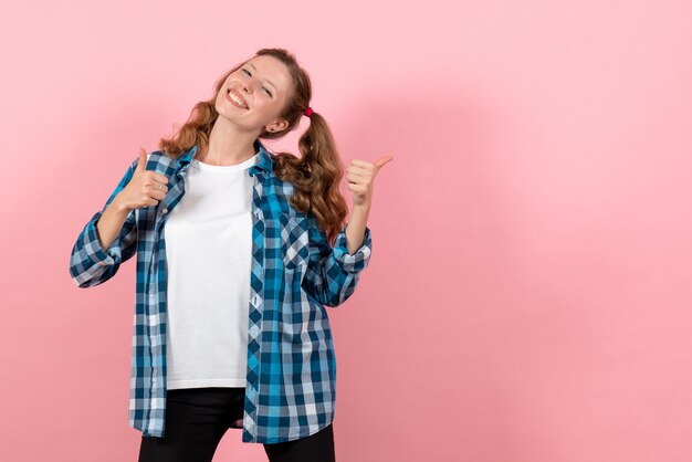 Vista frontal mujer joven en camisa a cuadros azul posando con una sonrisa sobre fondo rosa emoción niña modelo moda joven niño