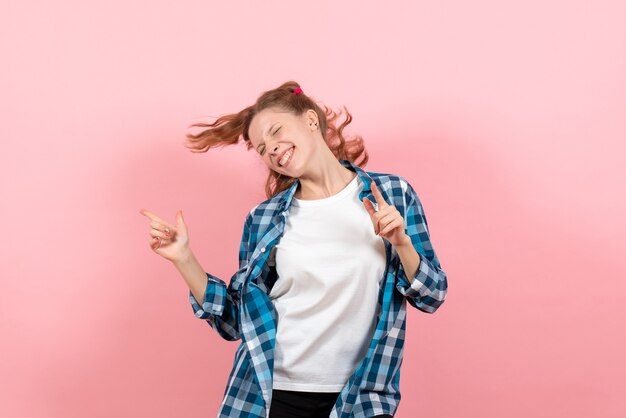 Vista frontal mujer joven en camisa a cuadros posando y bailando sobre fondo rosa modelo juvenil emociones mujer niño niña