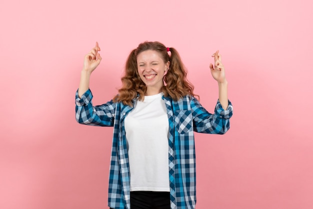 Foto gratuita vista frontal mujer joven en camisa a cuadros posando y cruzando los dedos sobre el fondo rosa mujer joven color emociones modelo infantil