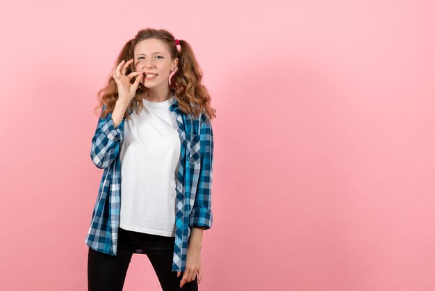 Vista frontal mujer joven en camisa a cuadros posando sobre fondo rosa modelo de emoción de color de mujer niño joven