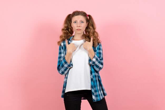 Vista frontal mujer joven en camisa a cuadros posando sobre fondo rosa modelo emociones niño joven mujer niña