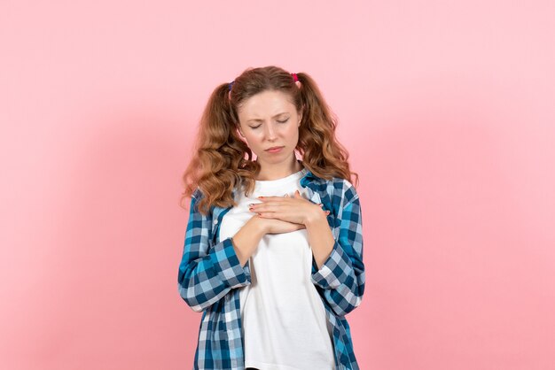 Vista frontal mujer joven en camisa a cuadros posando sobre un fondo rosa mujer joven color emociones modelo niño