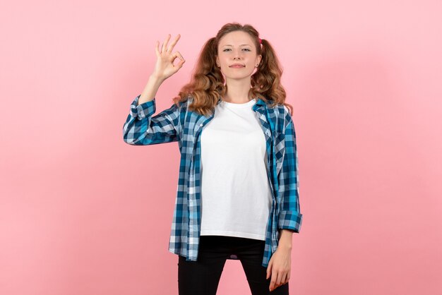 Vista frontal mujer joven en camisa a cuadros posando sobre fondo rosa mujer joven emoción modelo color de niño