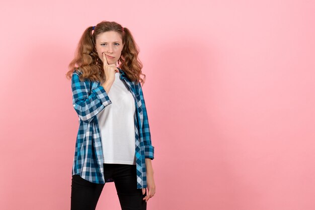 Vista frontal mujer joven en camisa a cuadros posando sobre fondo rosa mujer juventud color emociones modelo de niño