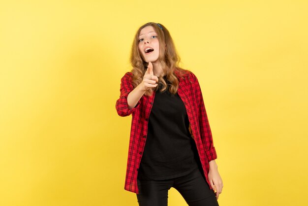 Vista frontal mujer joven en camisa a cuadros roja mostrando sus emociones sobre fondo amarillo modelo de emoción de color humano moda