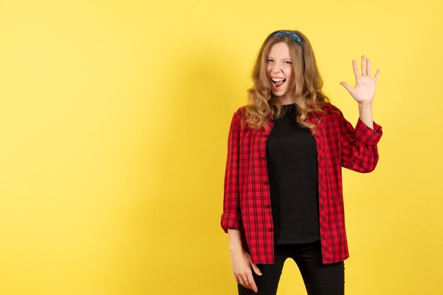 Vista frontal mujer joven en camisa a cuadros roja posando con emociones sobre fondo amarillo mujer emoción humana modelo moda chica