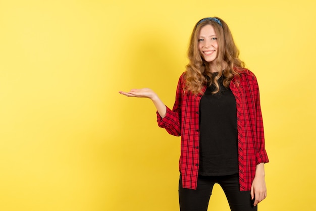 Vista frontal mujer joven en camisa a cuadros roja posando y mostrando sus emociones sobre fondo amarillo mujer emoción humana modelo moda chica