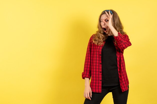 Vista frontal mujer joven en camisa a cuadros roja posando sobre fondo amarillo mujer emociones humanas modelo moda chica