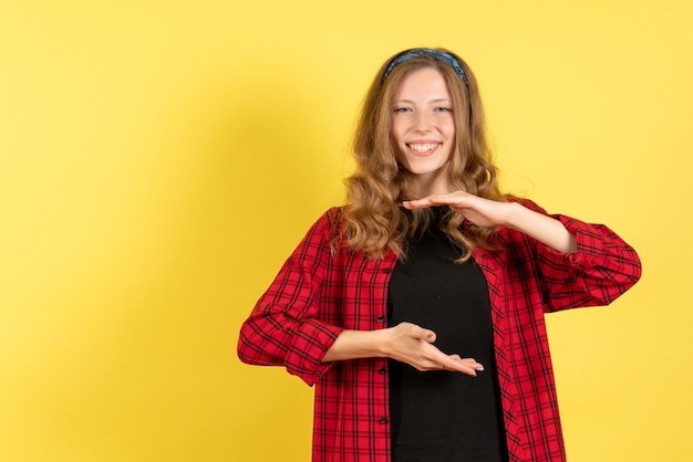 Vista frontal mujer joven en camisa a cuadros roja posando y sonriendo sobre fondo amarillo niñas mujer emociones modelo color humano