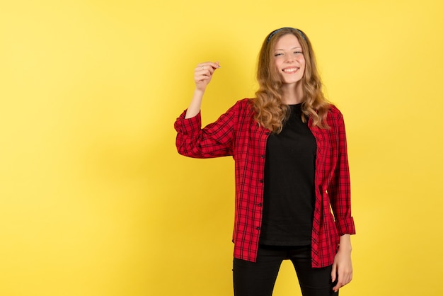 Vista frontal mujer joven en camisa a cuadros roja posando con sonrisa sobre fondo amarillo niña humana emociones color modelo mujer