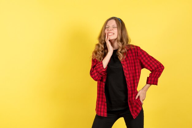 Vista frontal mujer joven en camisa a cuadros roja que sufre de dolor sobre fondo amarillo mujer emoción humana modelo moda chica