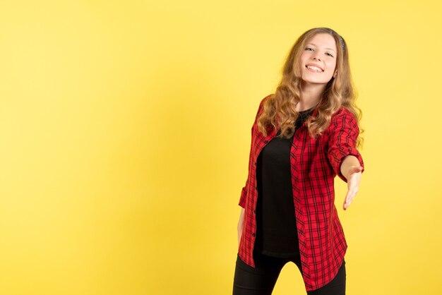 Vista frontal mujer joven en camisa a cuadros roja saludando a alguien sobre fondo amarillo mujer emoción humana modelo moda chica