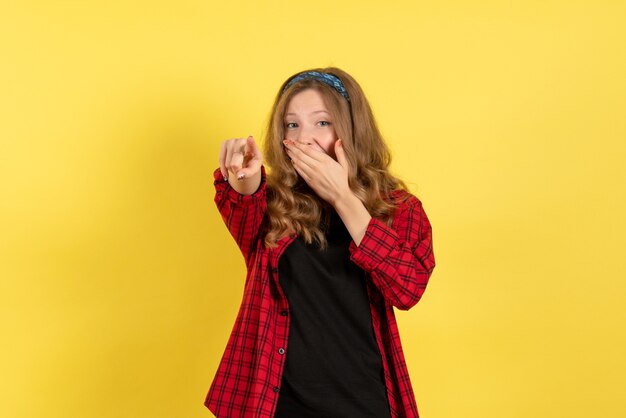 Vista frontal mujer joven en camisa a cuadros roja solo de pie y riendo sobre fondo amarillo niñas modelo de color humano mujer