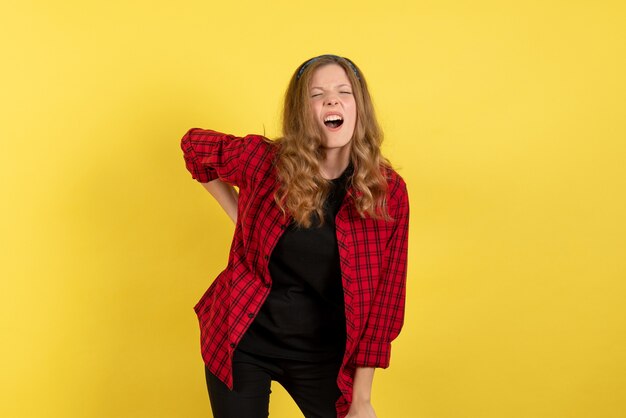 Vista frontal mujer joven en camisa a cuadros roja solo de pie sobre un fondo amarillo modelo niñas mujer humana color emociones