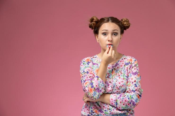 Foto gratuito vista frontal mujer joven en camisa de flor diseñada y jeans tocando sus labios en el fondo rosa