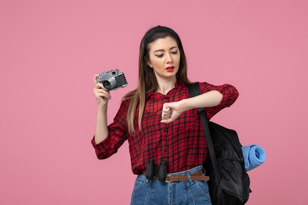 Vista frontal mujer joven en camisa roja con cámara en piso rosa modelo foto mujer