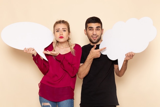 Foto gratuita vista frontal mujer joven en camisa roja junto con hombre sosteniendo carteles blancos en el espacio crema emoción fotográfica