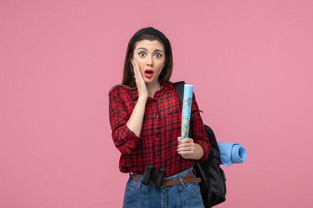 Vista frontal mujer joven en camisa roja con mapa en el color de moda de mujer de fondo rosa