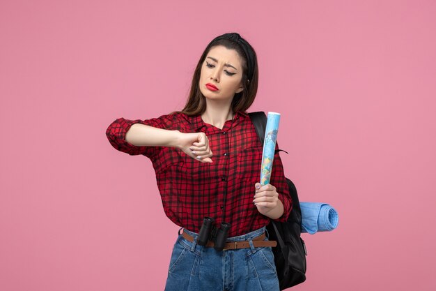 Vista frontal mujer joven en camisa roja con mapa en el color de moda de mujer de fondo rosa