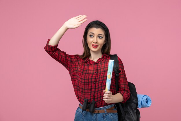 Vista frontal mujer joven en camisa roja con mapa en color rosa moda mujer de escritorio