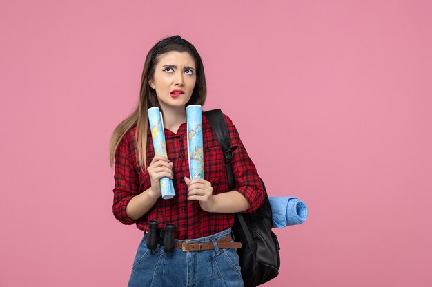 Vista frontal mujer joven en camisa roja con mapas en el color de fondo rosa mujer humana