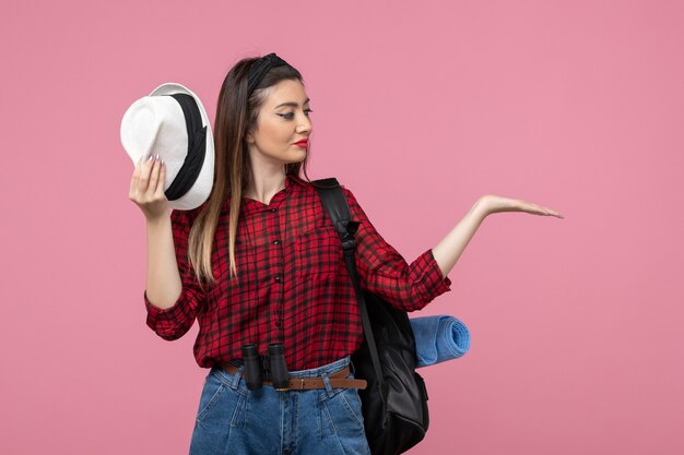 Vista frontal mujer joven en camisa roja con sombrero sobre fondo rosa colores mujer humana