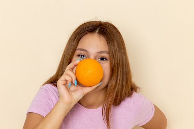 Vista frontal mujer joven en camiseta rosa y jeans con naranja