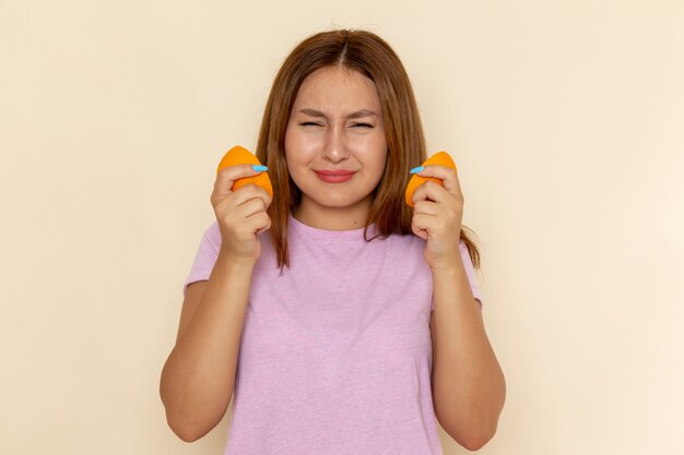 Vista frontal mujer joven en camiseta rosa y jeans con rodajas de naranja