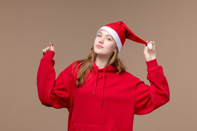 Vista frontal mujer joven con capa roja sobre fondo marrón Navidad emoción vacaciones