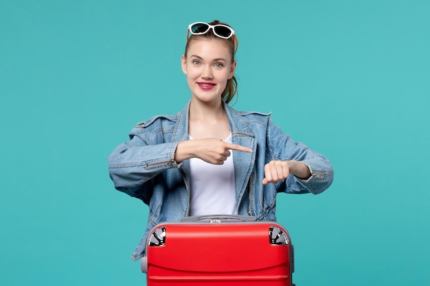 Vista frontal mujer joven en chaqueta azul preparándose para un viaje en el espacio azul claro