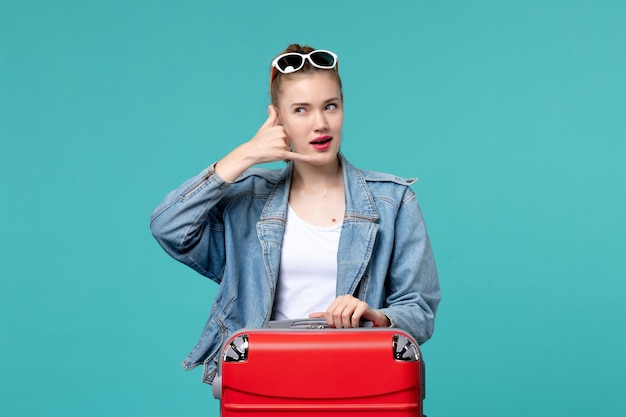 Vista frontal mujer joven en chaqueta azul preparándose para el viaje posando en el espacio azul