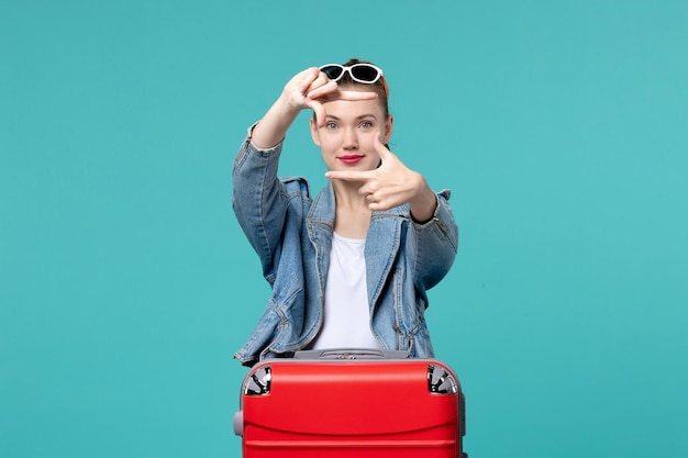 Vista frontal mujer joven en chaqueta azul preparándose para el viaje posando en el espacio azul