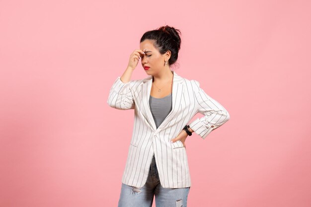 Vista frontal mujer joven con chaqueta blanca con dolor de cabeza sobre fondo rosa dama moda mujer emociones color