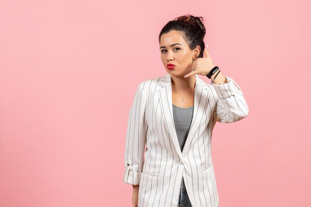 Vista frontal mujer joven en chaqueta blanca posando sobre fondo rosa dama moda colores mujer emoción