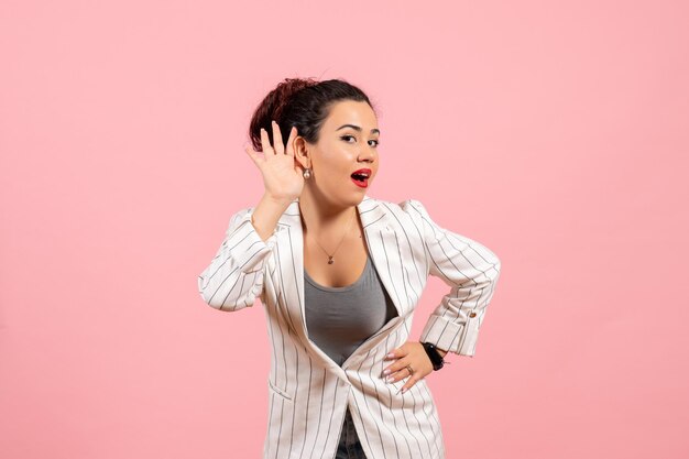 Vista frontal mujer joven en chaqueta blanca tratando de escuchar sobre fondo rosa dama moda color mujer emoción