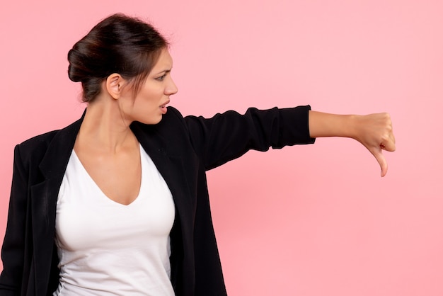 Foto gratuita vista frontal mujer joven en chaqueta oscura disgustado sobre fondo rosa