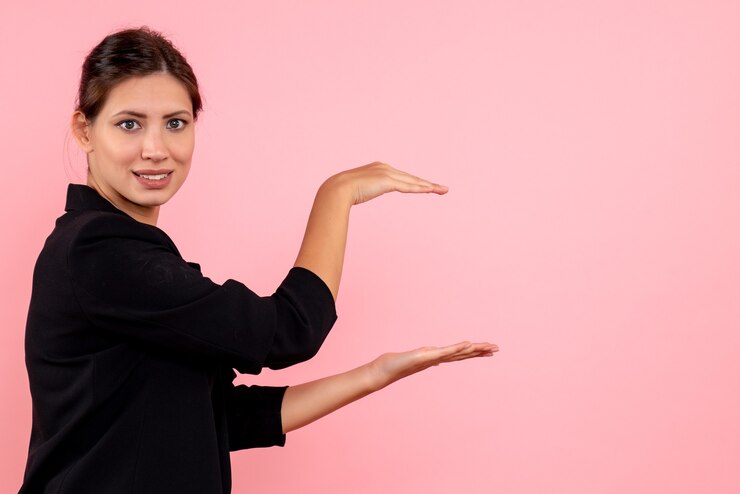 Foto gratuito vista frontal mujer joven en chaqueta oscura imitando que sostiene algo sobre fondo rosa