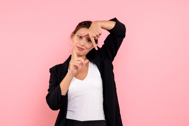 Foto gratuita vista frontal mujer joven en chaqueta oscura sobre fondo rosa