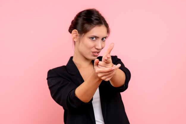 Vista frontal mujer joven en chaqueta oscura sobre fondo rosa