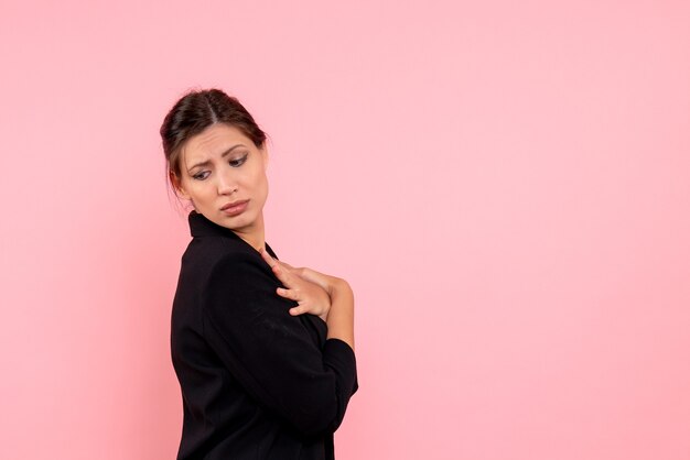 Vista frontal mujer joven en chaqueta oscura sobre fondo rosa