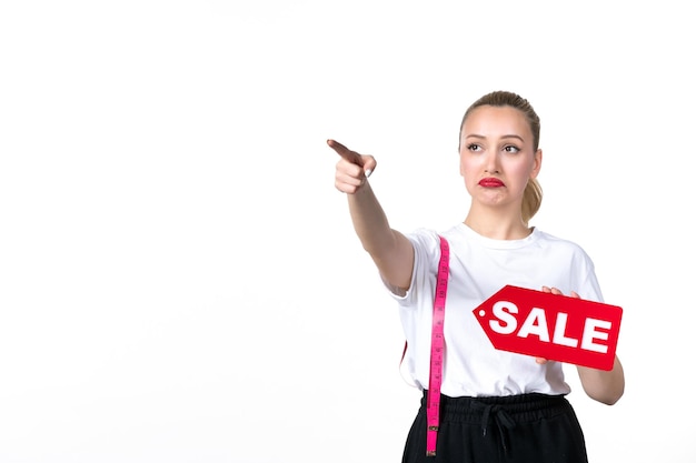 Foto gratuita vista frontal de la mujer joven con cinta métrica y placa de venta sobre fondo blanco midiendo el cuerpo de compras cintura centro comercial torso piel cadera peso colores