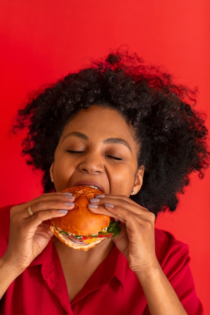 Vista frontal mujer joven comiendo hamburguesa