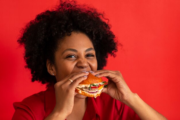 Vista frontal mujer joven comiendo hamburguesa