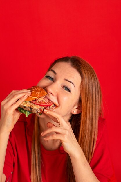 Vista frontal mujer joven comiendo hamburguesa